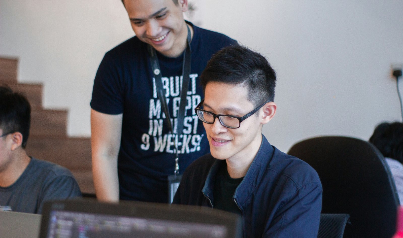 A mentor looking over a participant's shoulder at a screen