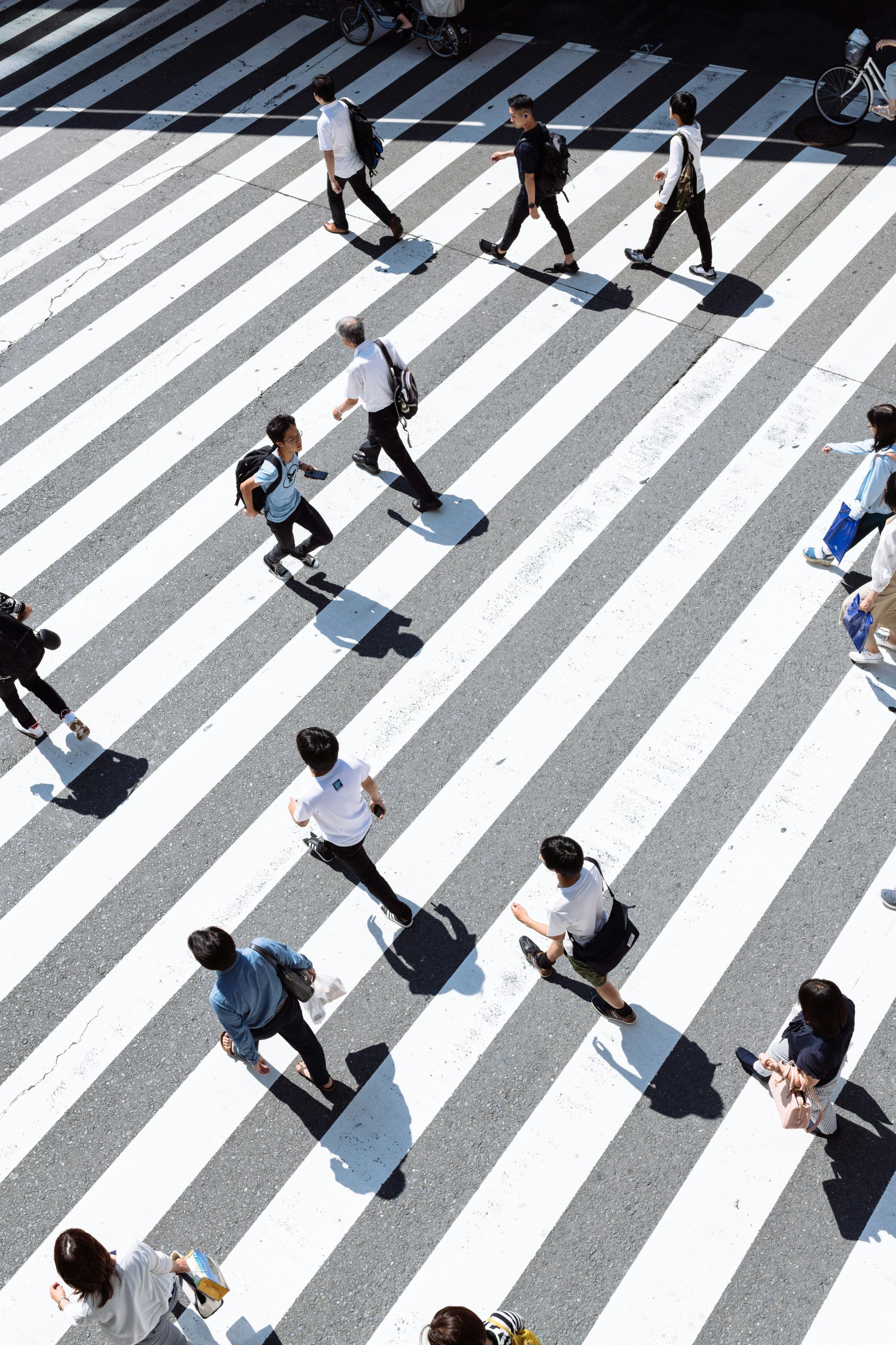 People crossing a wide diagonally striped intersection, seen from above